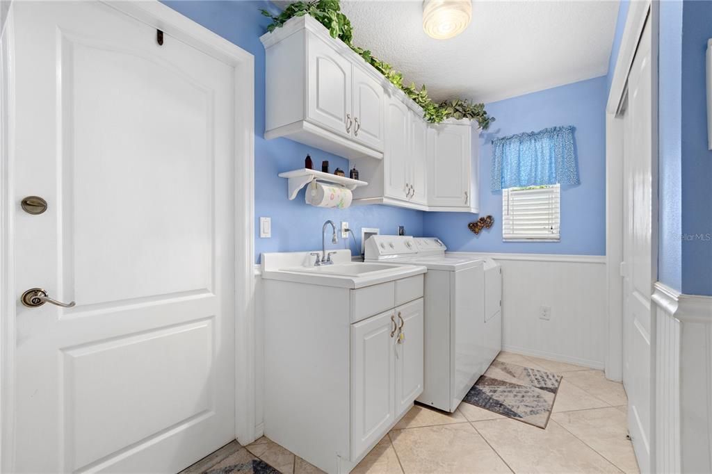 Laundry Room with Laundry sink, closet pantry, and cabinet space.  Door to garage,