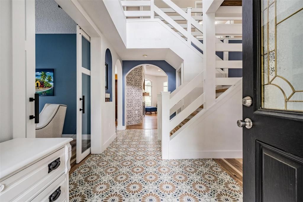 Stunning Entry way - Gorgeous new tile flooring, Custom Horizontal Stair Railing and laminate stair treads with solid wood nosing.  Office/Den/Living Room with Double Glass Barn Doors on the left