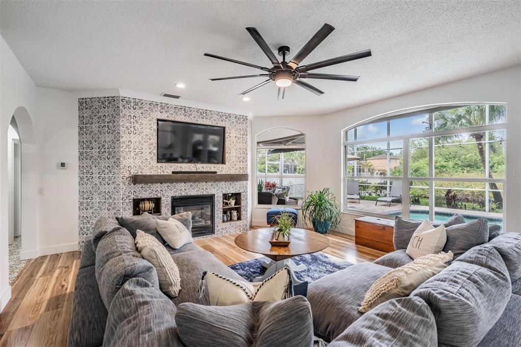 Huge, Open and lots of light in the Family Room, Custom Fireplace with new tile, Centered Fireplace and Shelving, New Water Resistant Laminate flooring, Ceiling Fan and views of the pool, conservation and pond.