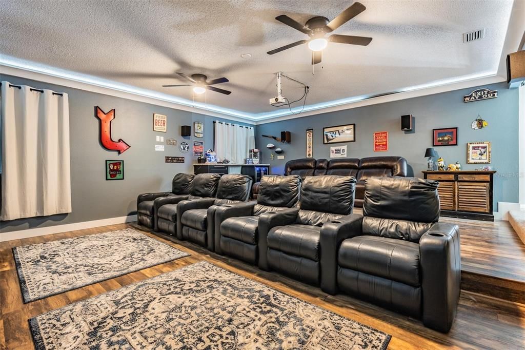 Huge Theater Room, new Flooring, Black out window curtains, ceiling fans and full bar area, up lights surrounding to tray ceiling, Remodeled space with tiered flooring to accommodate seating for 10Surround lighting and 100 Viewing Screen