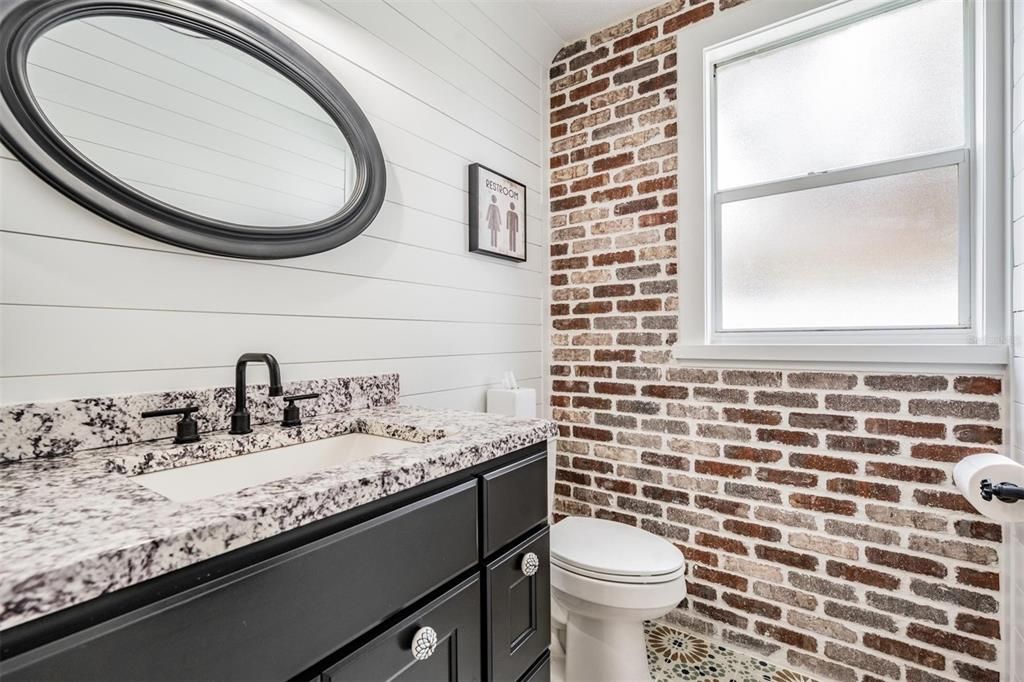 Downstairs Guest bathroom completely renovated with new sink, mirror, shiplap wall, brick wall and tile flooring.
