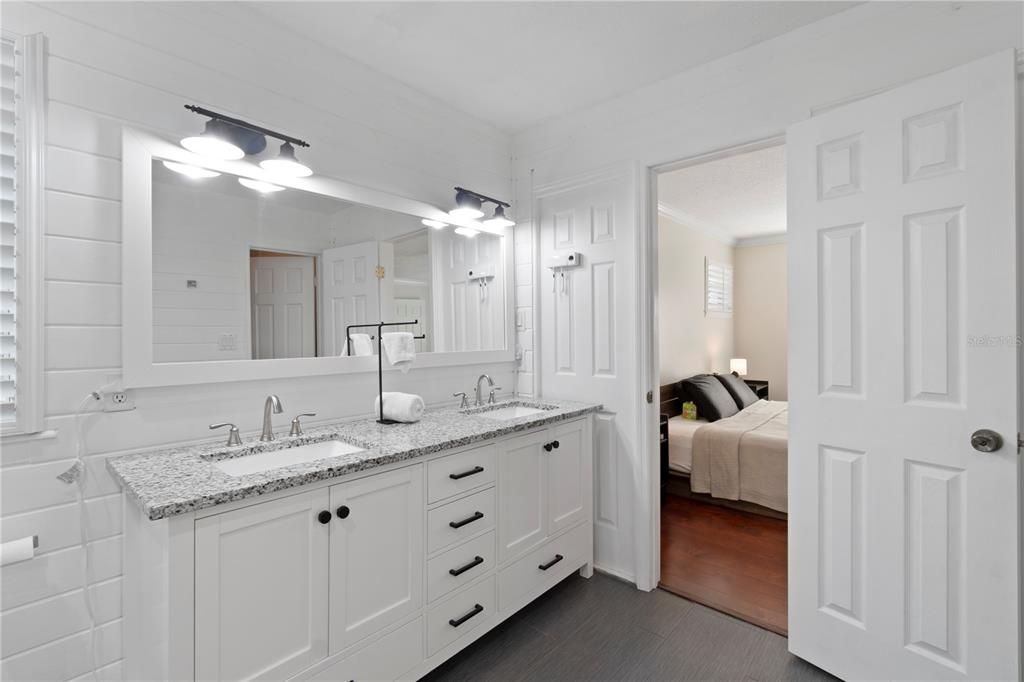 The master bathroom boasts a double vanity sink and updated flooring, complemented by clean stone countertops.