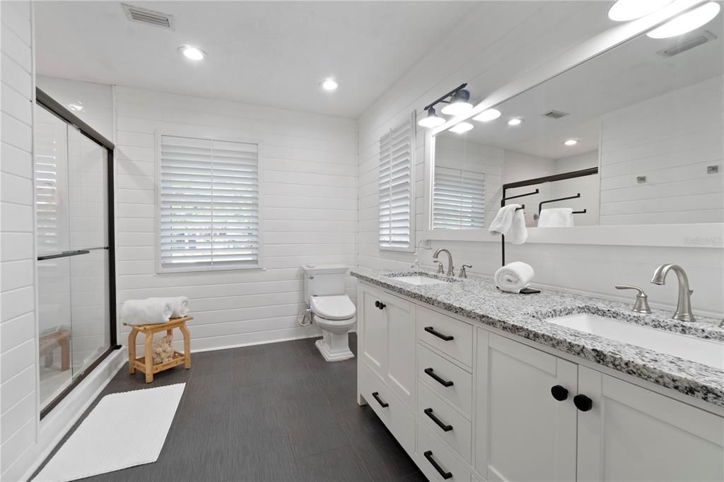 The master bathroom boasts a double vanity sink and updated flooring, complemented by bright tile work in the shower.