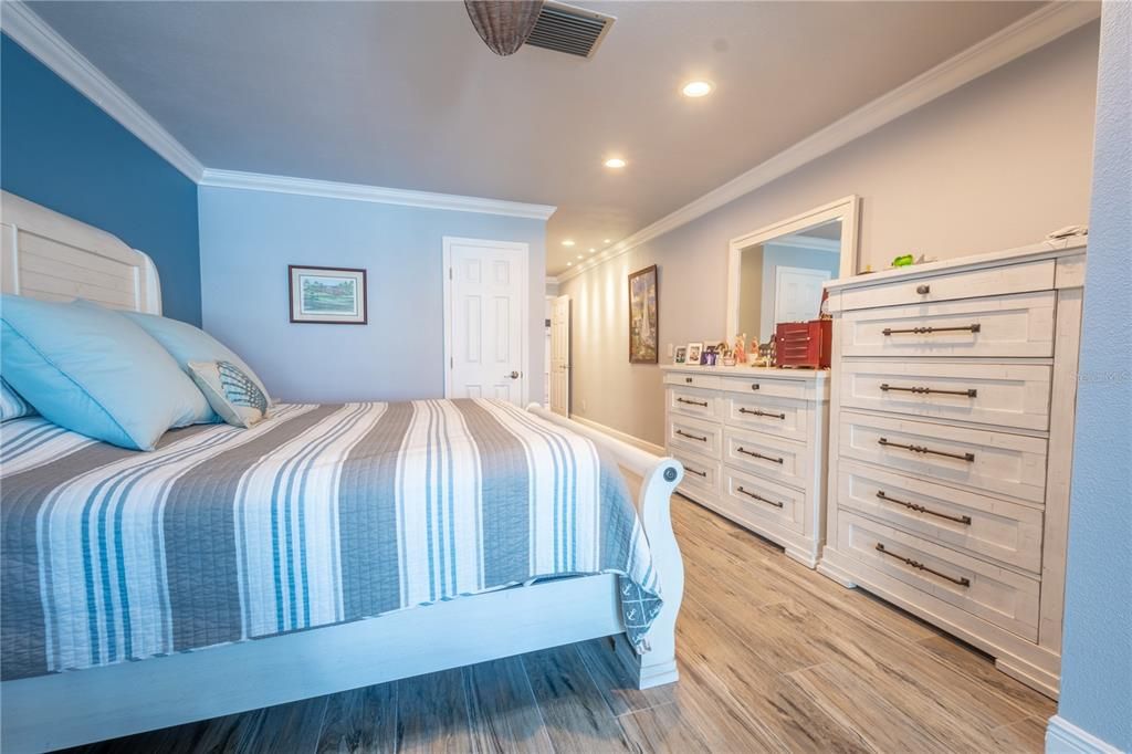 The primary suite features recessed lighting, crown molding and a ceiling fan.