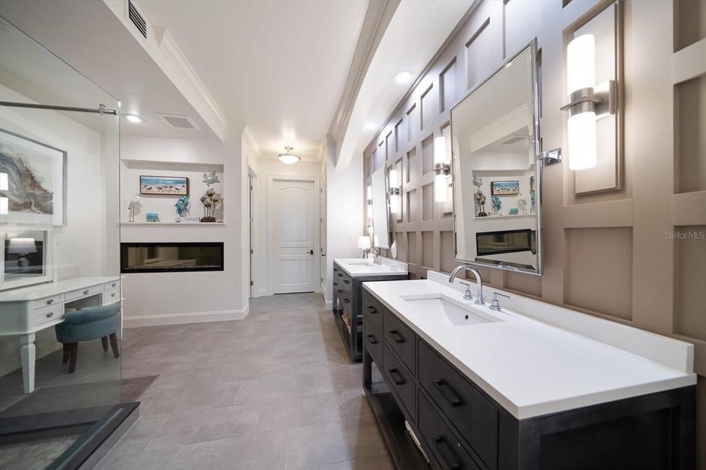 Spa like primary bath area.. Double vanities, intricate paneling and inviting electric fireplace.