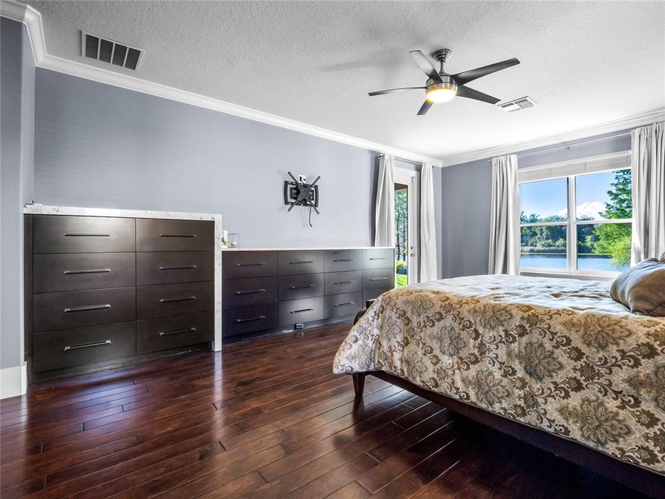 Master Suite with pendant lights, access to lanai, luxury wood flooring, built in dressers with marble top and access to the Lanai, custom built closet and spa bathroom