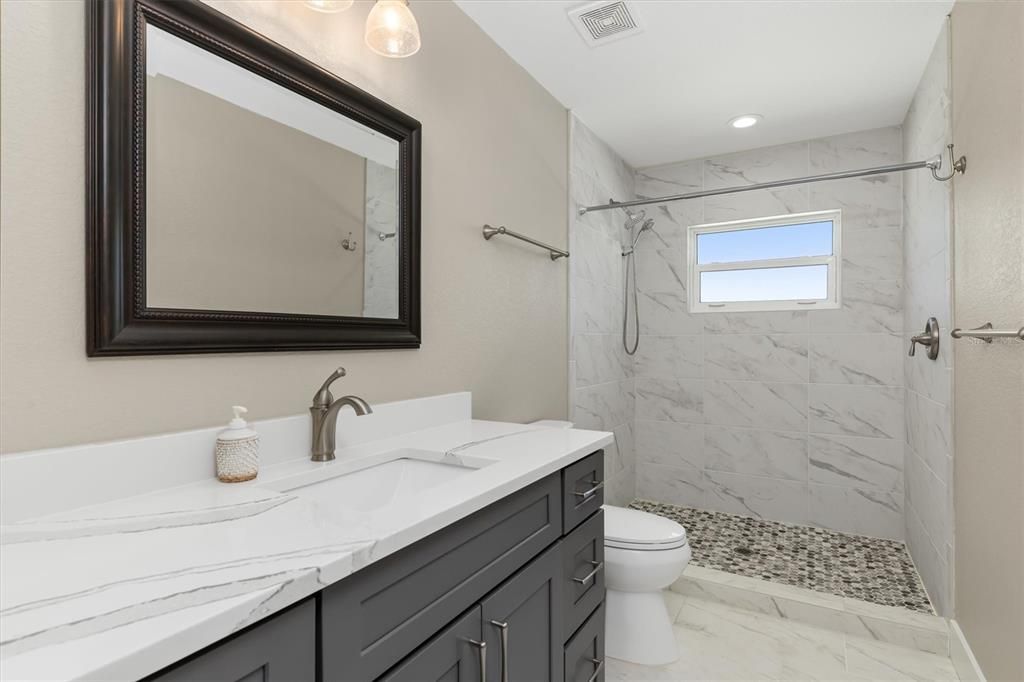 Upstairs bathroom offers walk-in shower and cabinetry and countertops that coordinate with kitchen.