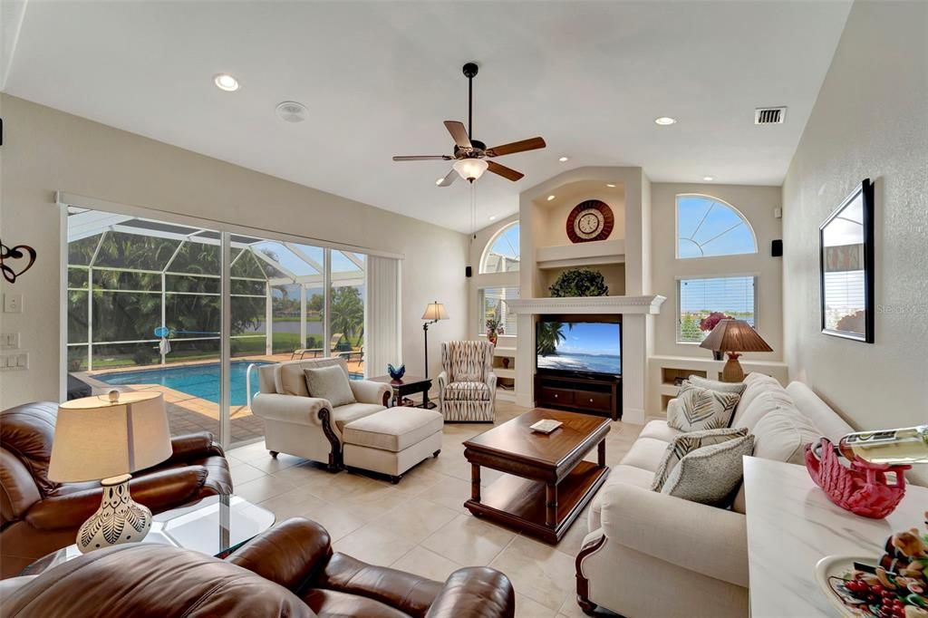 LARGE FAMILY ROOM WITH CUSTOM BUILT-INS, A LARGE SET OF SLIDERS AND A VIEW TO THE LAKE