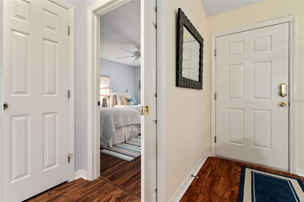 FRONT DOOR (far R) & POCKET DOOR ENTRANCE to guest wing (center). HALLWAY leads to BATHROOM #2 (L) - not visible, CLOSET (back L) for extra storage, and entrance to BEDROOM #2 (back R).