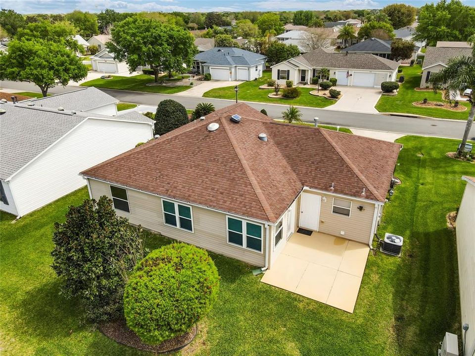 Low AERIAL of REAR EXTERIOR shows large open patio perfect for BBQ grilling & alfresco dining.