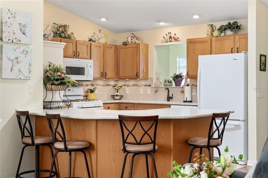 KITCHEN features OAK WOOD CABINETS w/ underlighting & PULL OUTS, TILE BACKSPLASH, High Definition LAMINATE COUNTERTOPS, custom white, stand alone PANTRY, & WHITE APPLIANCES.