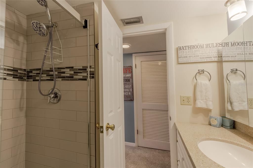 Discover a beautifully Renovated Bathroom, with lovely cabinets, lighting, porcelain tile flooring, sliding glass shower enclosure, a skillfully designed tiled shower and dual shower heads.