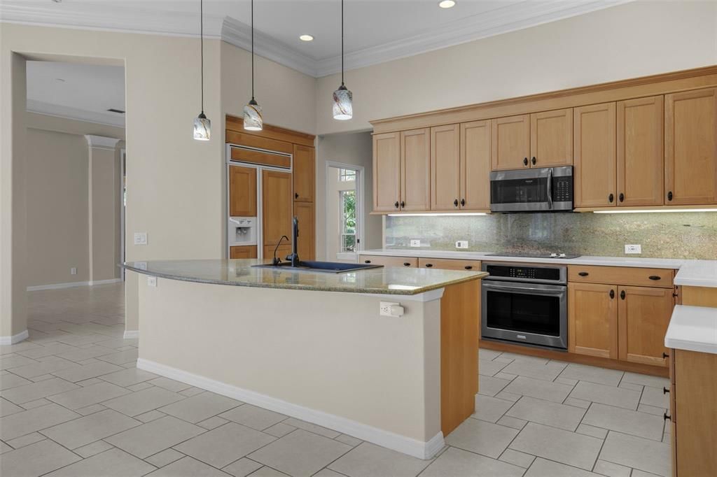 View of kitchen with dining room beyond.  To left is eat-in area overlooking pool/golf course.