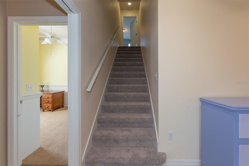 Stairs and hallway  off the family room lead to three guest bedrooms