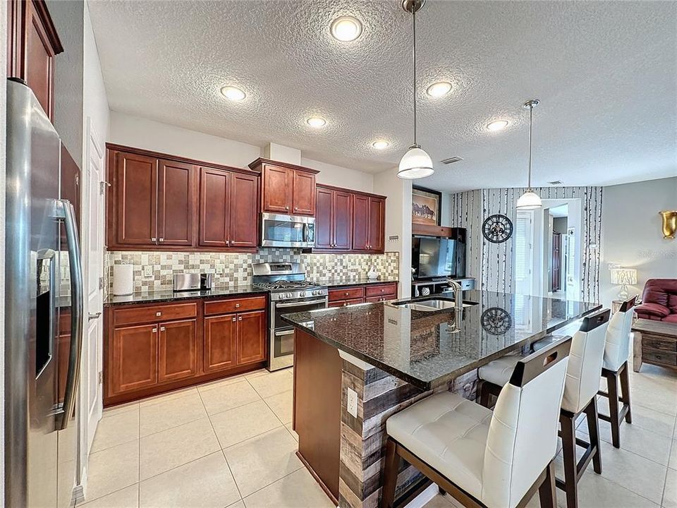 WELL-APPOINTED KITCHEN boasts 42” WOOD CABINETS with HARDWARE, UNDERLIGHTING, CROWN MOLDING and DESIGNER BACKSPLASH