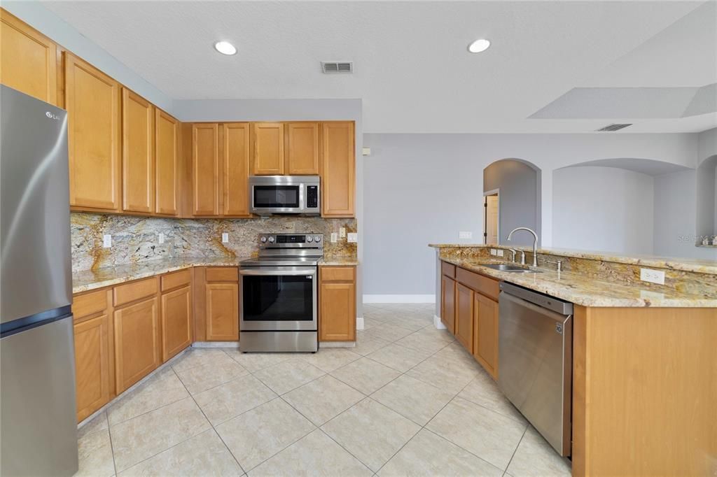 The home chef will appreciate the ample storage provided by the 42” cabinetry and closet pantry, there are STAINLESS STEEL APPLIANCES, stone counters and backsplash and the large island has additional casual seating at the bar.
