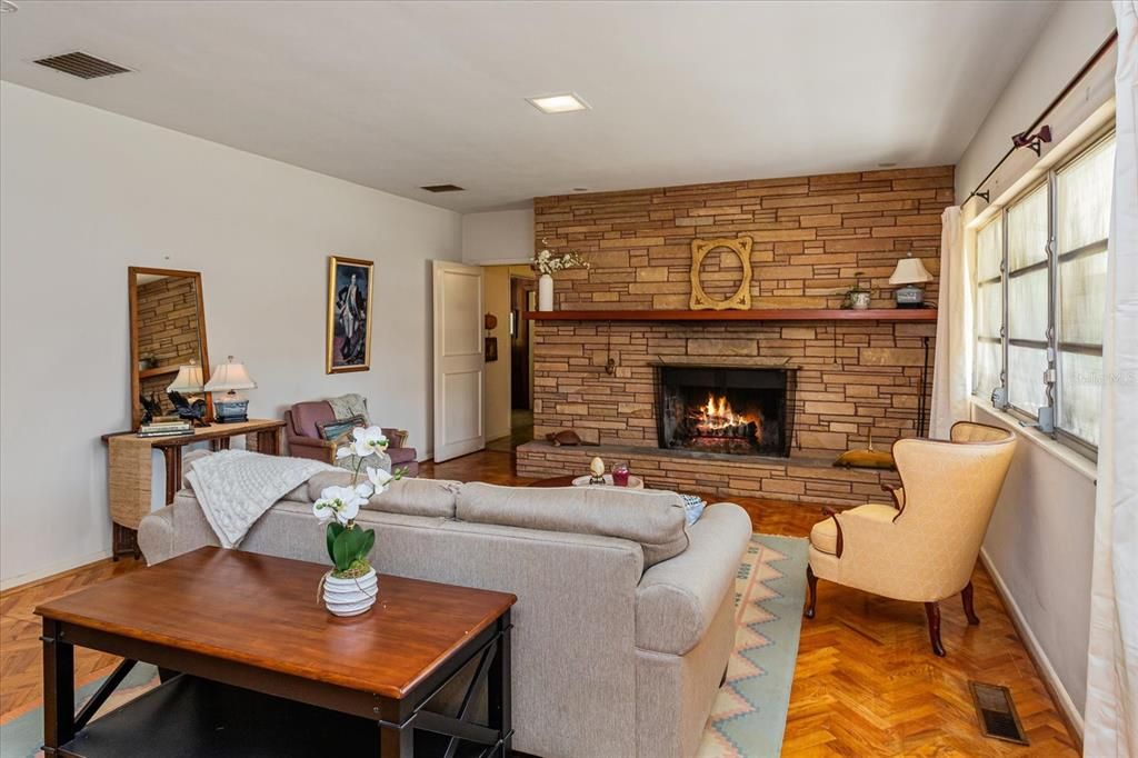 living room has wood flooring and stone wall fireplace.