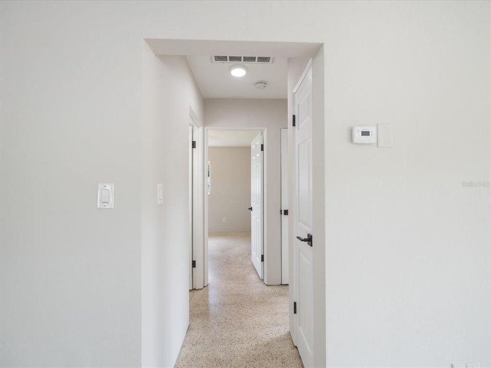 Hallway to full bath and two bedrooms