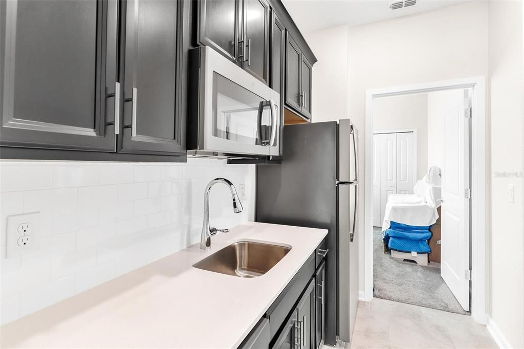 In law kitchenette features sink, microwave, cabinets, dishwasher, refrigerator, and stackable washer & dryer