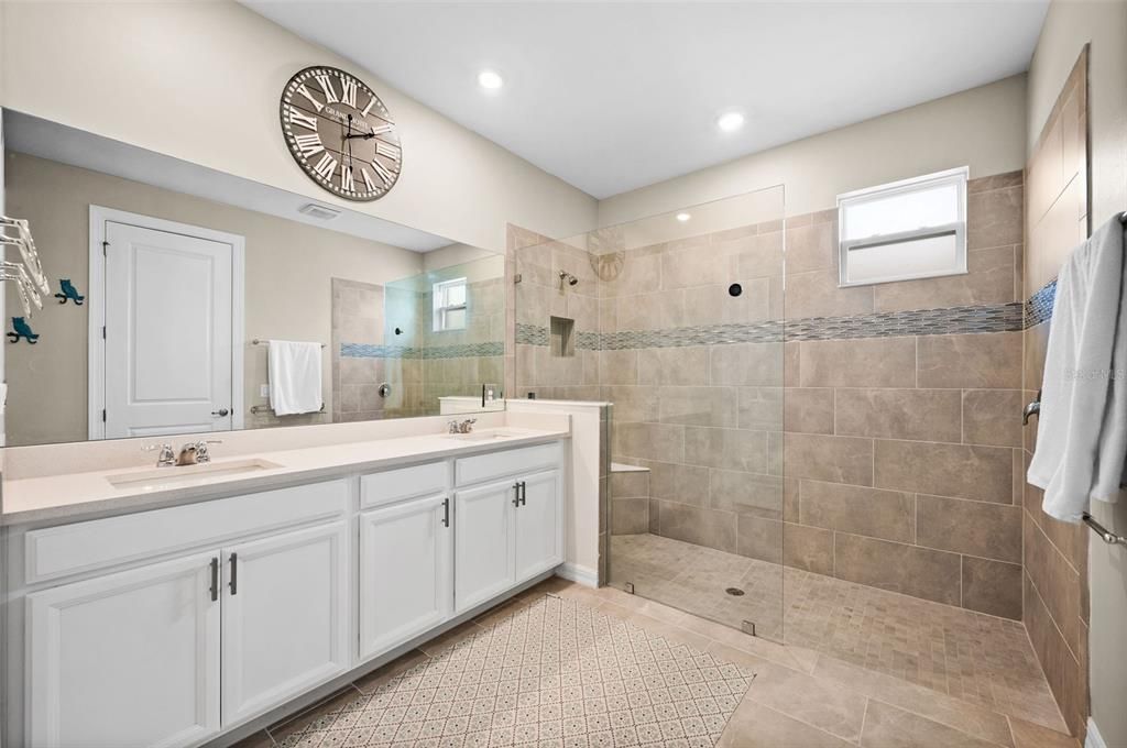 master bathroom with double vanities, extended shower with bench