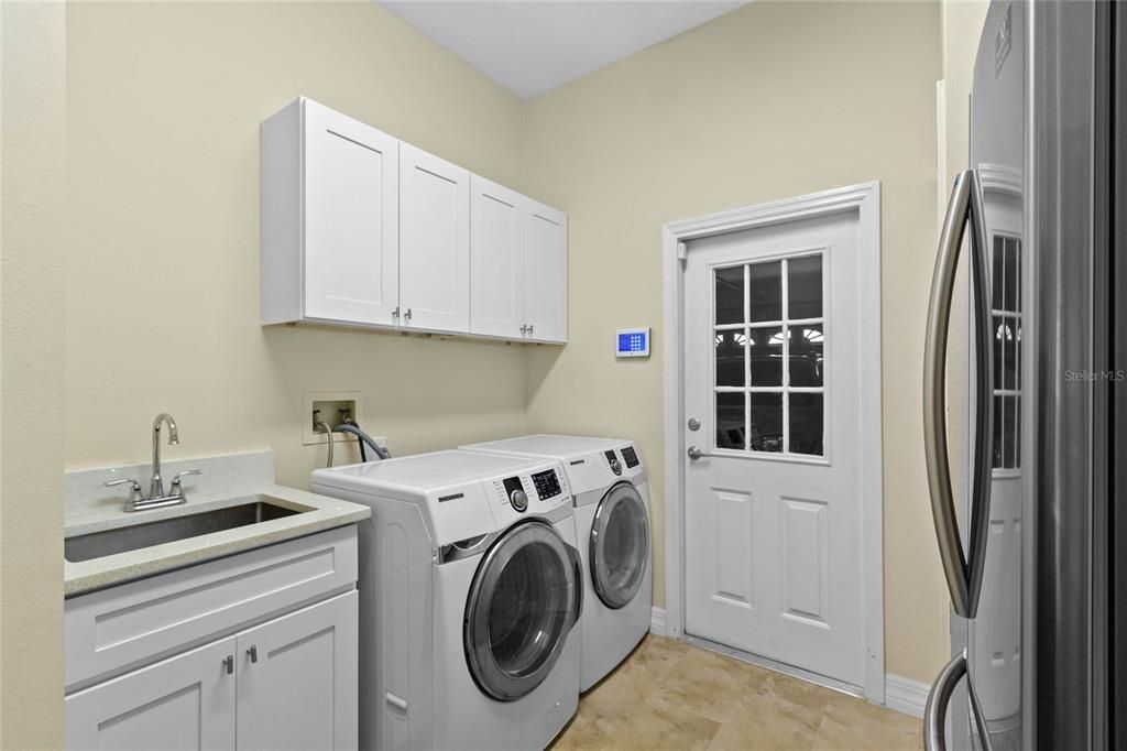 This home features a spacious laundry area with a second fridge and garage access.