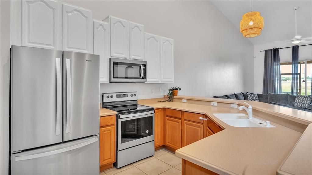 Kitchen open to living room with corian counter tops and stainless appliances.