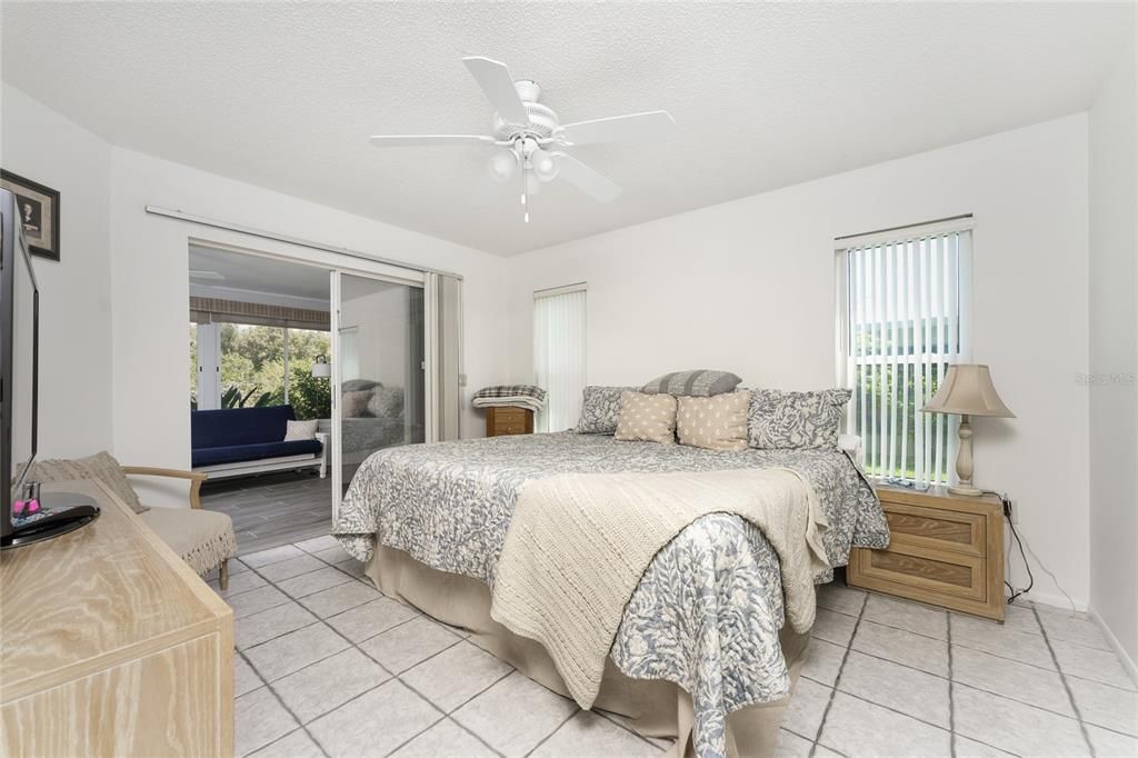 Master bedroom has tiled flooring and sliding glass doors opening onto the Florida Room