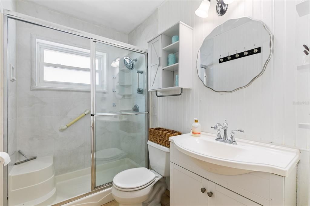 The full bath features a sleek modern vanity and a walk-in shower with a convenient corner seat.