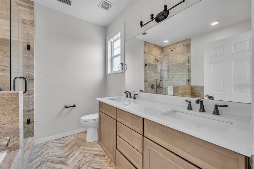 2nd Floor primary en-suite offers dual sink, granite topped vanity with walk-in shower and soaker tub.