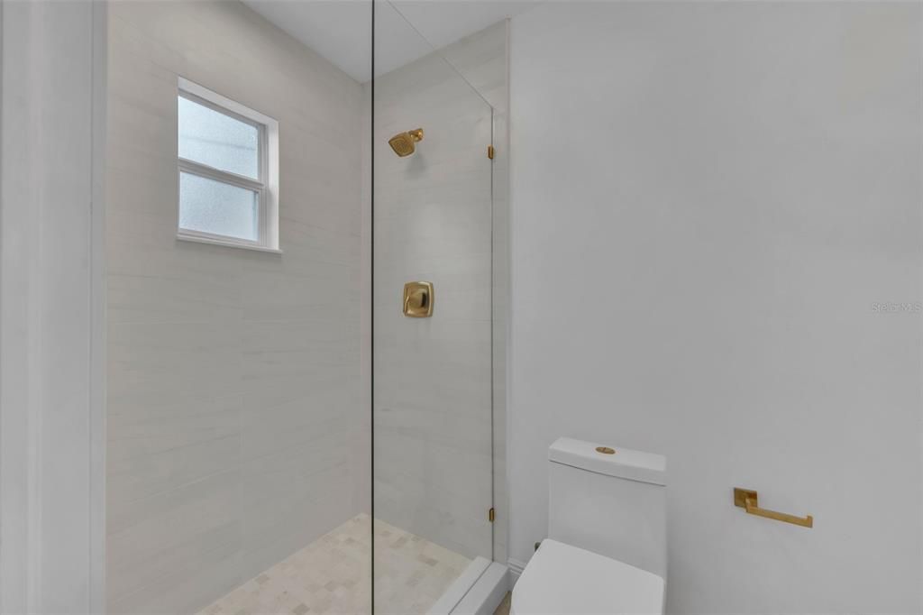 Gold accent fixtures offer the latest in design trends in this beautiful walk-in shower.