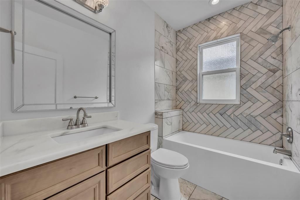 Main Floor Bathroom with marble tile and granite vanity top.
