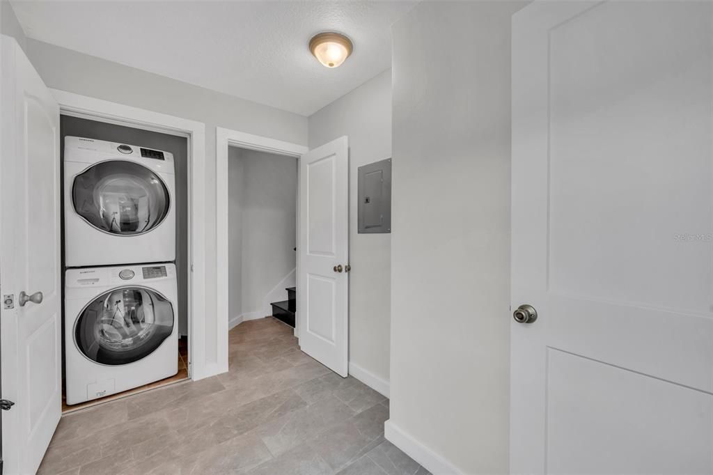 Side entrance from driveway opens to a utility area that includes laundry and separate lockable entrances leading to the kitchen of the main living area of the home (on the right) and to the 2nd floor bedroom suite.