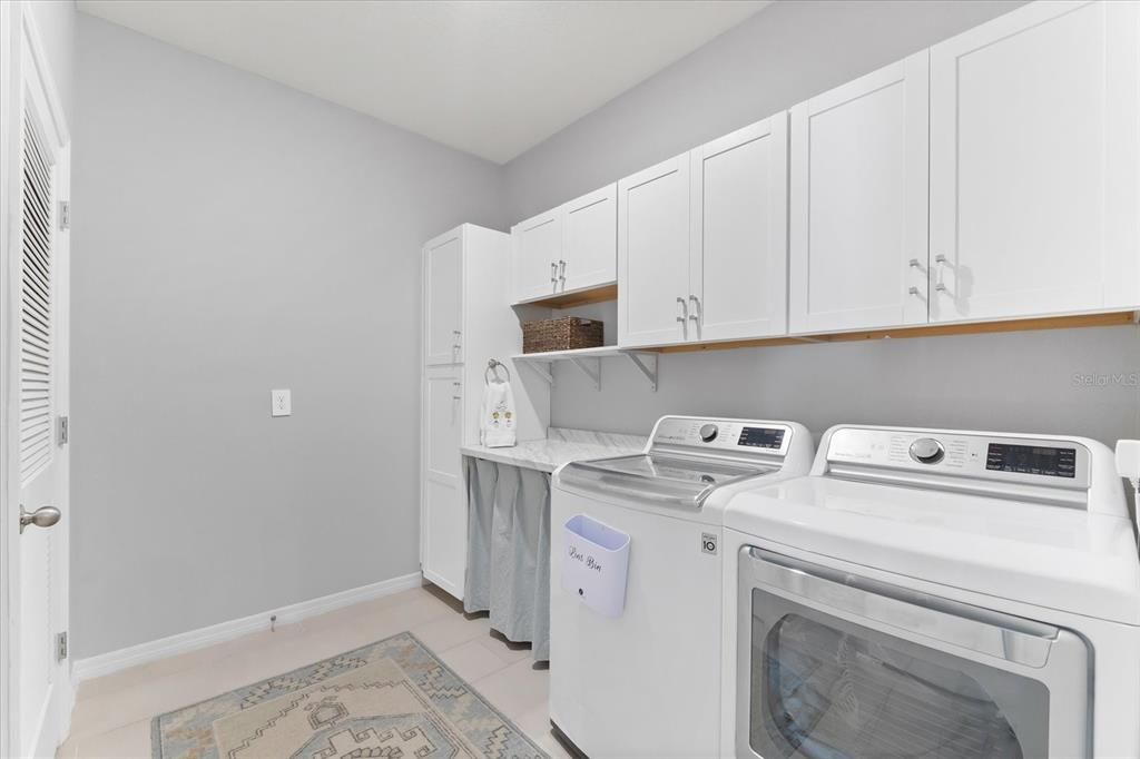 Spacious laundry room with added cabinets and stone countertop.