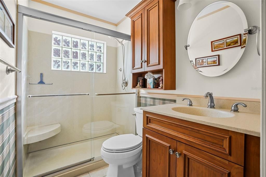 Guest bath with walk-in shower updated vanity and medicine cabinet, tile and pretty window offering natural light.