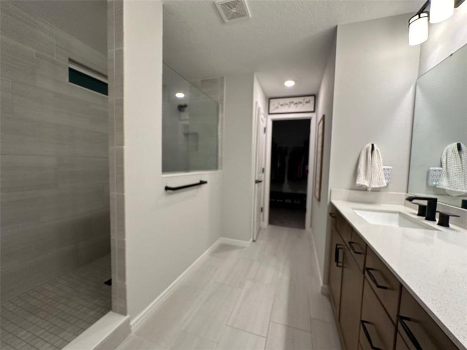 upstairs main bathroom with dual sink vanity, super shower, private toilet area, and walk in closet