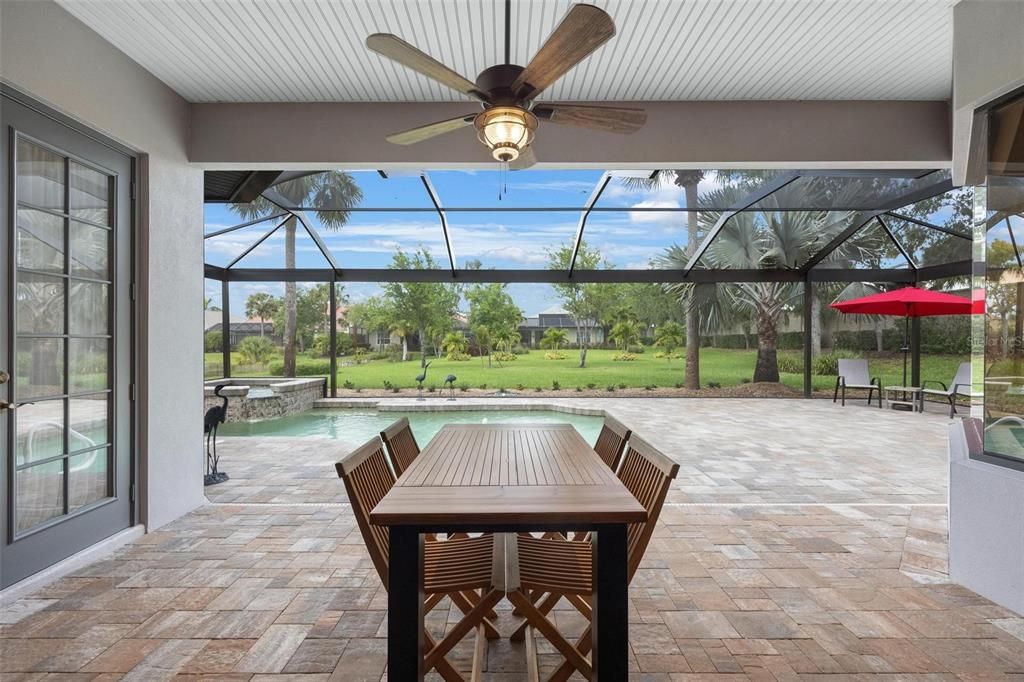 Through the sliding doors of the Living Room, or Owner's suite you are invited to this covered pool deck area. Notice the pavers that continue the warmth from the inside, and the picture screen enclosure. All the extras are already here.