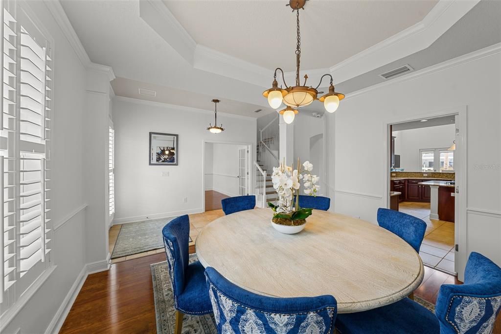 Elegant dining room features hardwood floors, plantation shutters, and tray ceiling. Cut-through door to kitchen offers convenience.