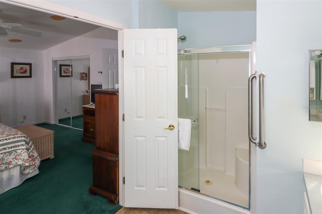 Double doors to primary bath with step in shower with bench