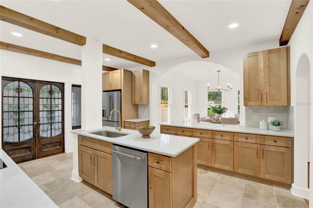 The modern cabinetry and clean lines of the kitchen coupled with the wood beam ceiling accents and enchanting light fixtures create a timeless look and cohesive flow throughout the home.
