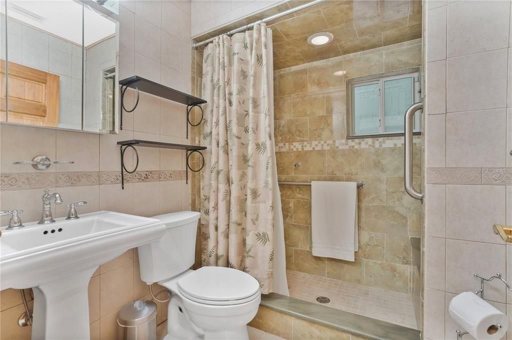In-Law residence full bath featuring a shower with floor to ceiling tile.