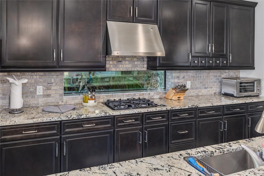 Gas range kitchen with abundant cabinetry and granite countertop space