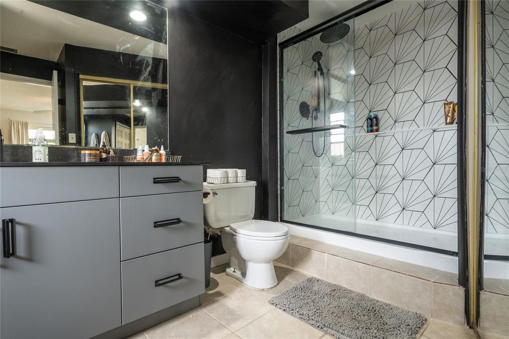 The updated primary bathroom has a modern walk-in glass shower and single vanity