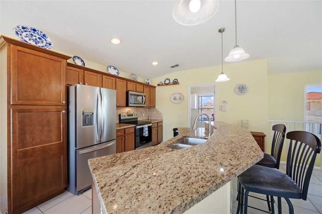 Spacious kitchen with granite countertops, solid wood cabinets, pendant lights, a breakfast bar, & NEW Fingerprint Resisitant Stainless Steel Appliances.