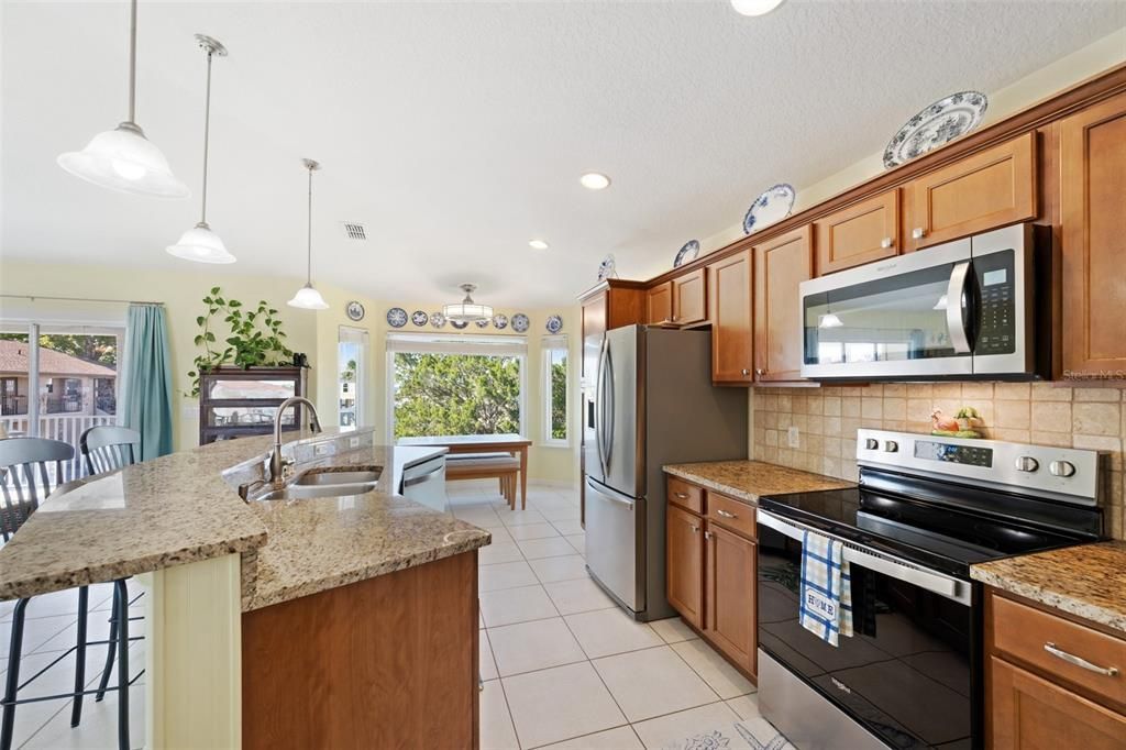 Spacious kitchen has granite countertops, solid wood cabinets, pendant lights, a breakfast bar, & NEW Fingerprint Resisitant Stainless Steel Appliances.