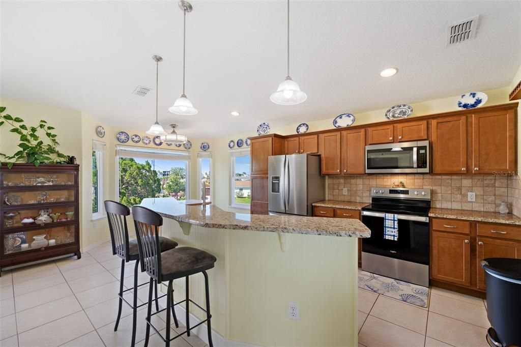 Spacious kitchen with granite countertops, solid wood cabinets, pendant lights, a breakfast bar, & NEW Fingerprint Resisitant Stainless Steel Appliances.