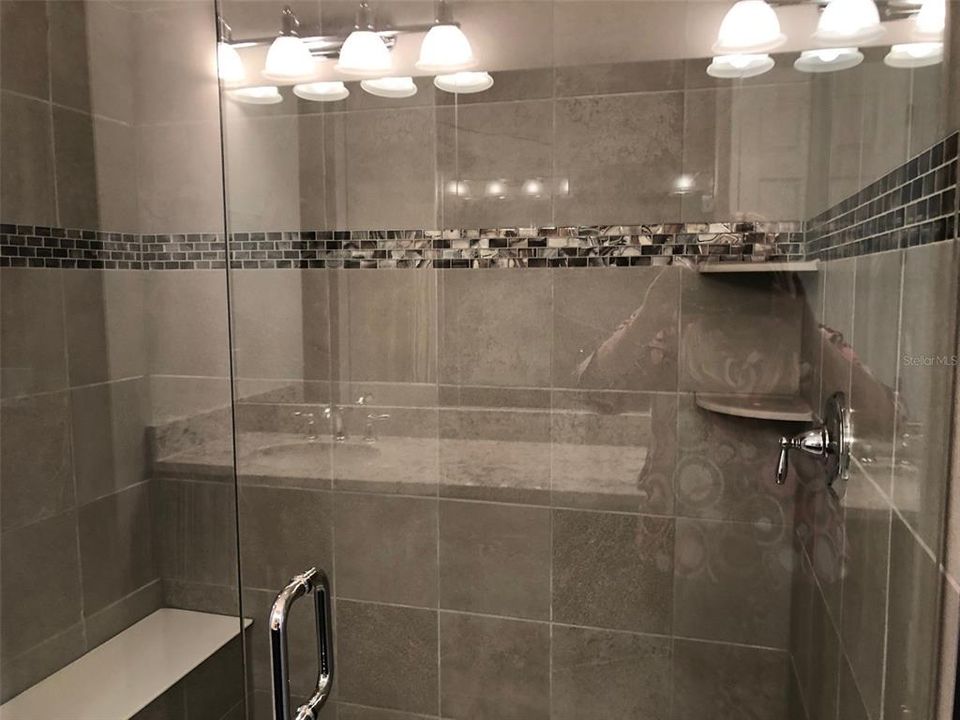 This beautiful custom tiled shower which frame less enclosure and convenient built-in bench.