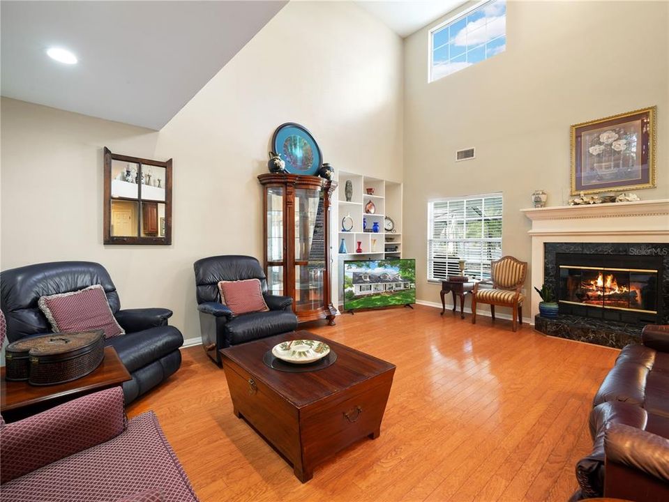 Soaring ceilings in family room with wood burning fireplace.