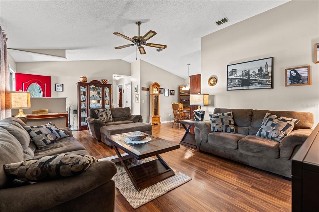 Living room features high cathedral ceiling and laminate flooring.