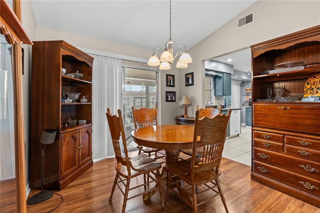 The dining room features wood laminate flooring and flows through the living room and kitchen
