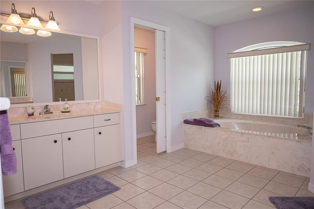Primary bathroom with dual vanities, tub, shower and separate toilet room